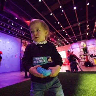 Young Child at Baby Rave Event Under Neon Lights