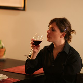 Woman Savoring Red Wine at Dinner Table