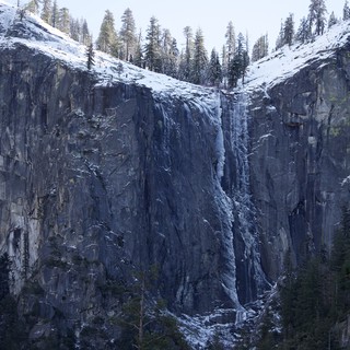 Frozen Waterfall on Snow-Covered Granite Cliff Face