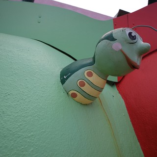 Whimsical Green Caterpillar Sculpture on Colorful Wall