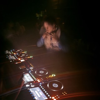 DJ Performance in Dark Club with Illuminated Controllers