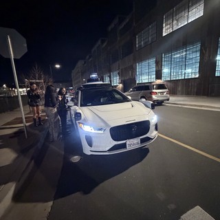 Autonomous Jaguar I-PACE at Night with Onlookers