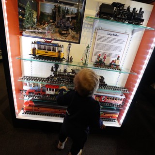 Child Explores Vintage Train Models at Museum Display