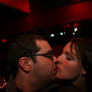 Couple Sharing a Kiss in Red-Lit Bar