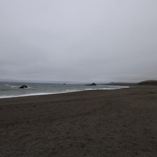 Moody Overcast Beach with Dark Sand and Ocean Rocks