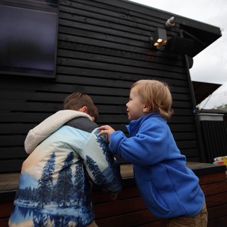 Two Children in Blue Coats at Outdoor Venue