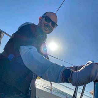 Captain Dave soaking up the sun Caption: Dave B, a skilled sailor and hard worker, takes a moment to enjoy the beautiful blue sky and sunshine on his sailboat adventure. Donning his trusty hat and stylish sunglasses, Dave basks in the beauty of the great outdoors.
