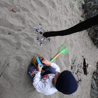 Young Explorer Plays in the Sand by Rocky Shore
