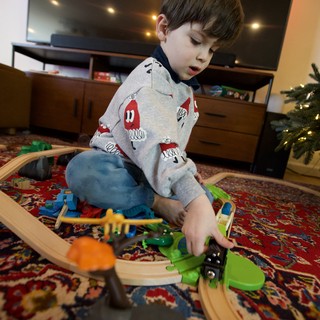 Young Boy Playing with Wooden Train Set at Christmas