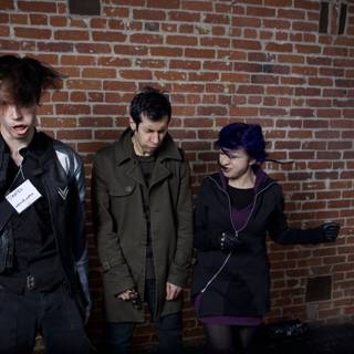 Three People Posing Against a Brick Wall