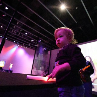 Toddler Mesmerized by Interactive Museum Exhibit at Night