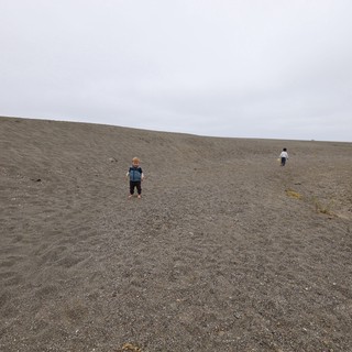 Two Children Exploring a Vast Gray Sand Dune
