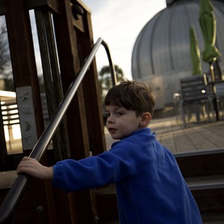 Young Boy at Modern Playground Structure at Dusk