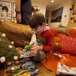 Child Opening Christmas Stocking on Cozy Living Room Sofa