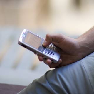 Connected Man Caption: A male adult stays connected with his mobile phone by texting on it, in a 2006 Flexilis shoot.
