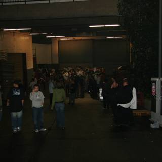Group of People in a Parking Lot Caption: John Petrucci (center) stands among a crowd of 20 people wearing jeans and various accessories, outside a factory building in New York on New Year's Eve of 2005.