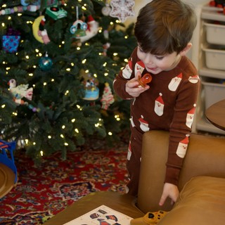 Young Child Opening Christmas Present by Decorated Tree