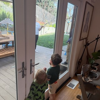 Two Children Watching Parents Work in Backyard