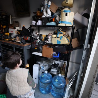 Young Child Exploring Cluttered Workshop Shelving Unit