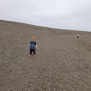 Toddler Smiling on Vast Gray Sand Dune