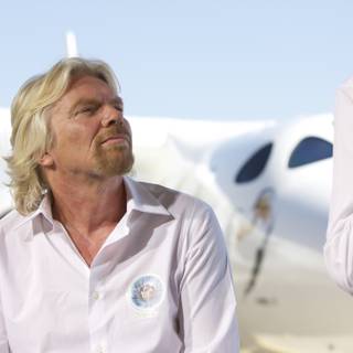 Two Men in White Shirts next to a Blue Sky Plane