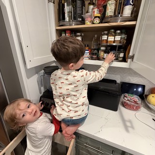 Two Young Boys Exploring Kitchen Cabinet Together