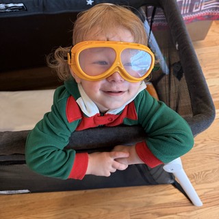 Joyful Toddler in Aviator Goggles and Green Sweater