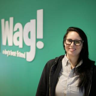 Woman in Glasses Poses in Front of Wag Logo