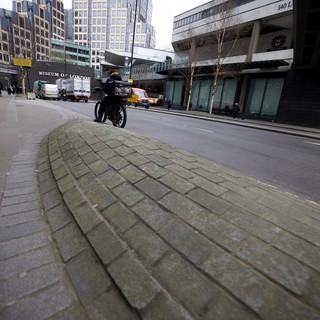 Motorcyclist Rides Past Museum of London in Urban Scene