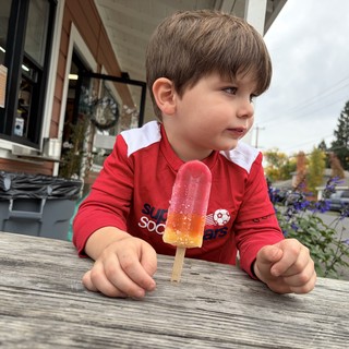 Young Boy Enjoying Colorful Popsicle on Outdoor Deck
