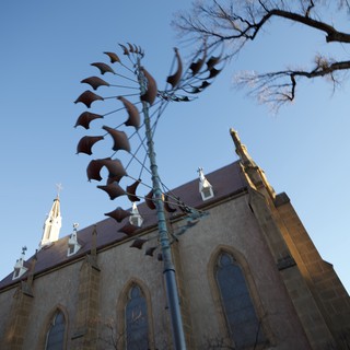 Metal Phoenix Sculpture Against Historic Church at Dusk