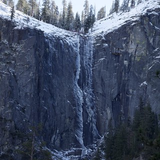 Frozen Waterfall Cascading Down Snow-Covered Basalt Cliffs