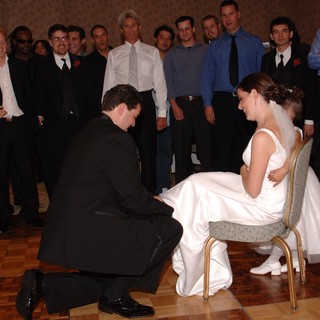 Groom Removes Garter from Bride at Wedding Reception