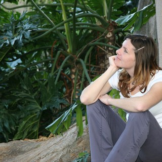 Contemplative Woman Resting Against Wall in Tropical Garden
