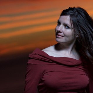 Woman in Red Beneath a Dramatic Sunset Sky