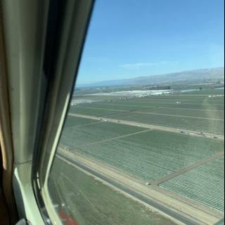 Aerial View of a Field and Highway from an Airplane Window