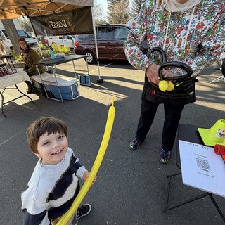 Young Boy Enjoys Balloon Sword at Community Market Event