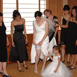 Bride Adjusts Garter Surrounded by Wedding Party