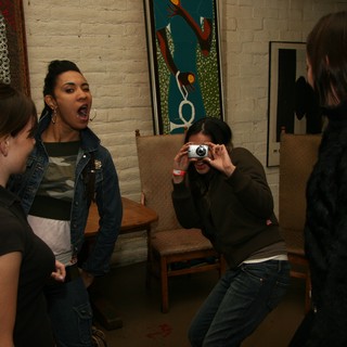 Friends Laughing and Photographing at Indoor Gathering