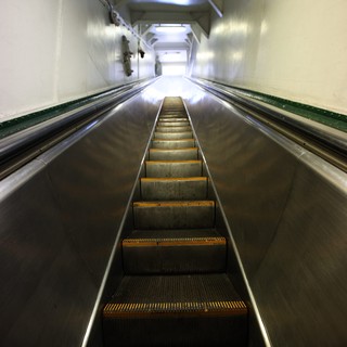 Ascending the Steep Escalator into Illuminated Transit Tunnel