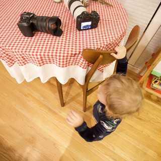 Young Child Reaching Toward Camera Equipment on Table