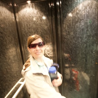 Smiling Woman in Elevator Holding Water Bottle