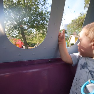 Young Child Gazing Through Playground Window at Park