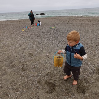 Toddler Explores Beach with Yellow Bucket