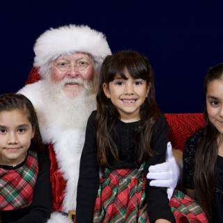 Santa Claus takes a picture with three adorable girls