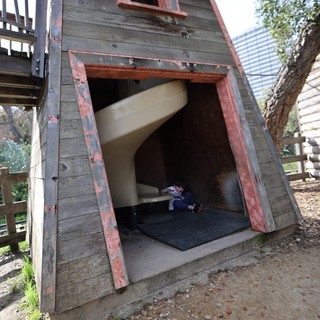 Child Playing in Weathered A-Frame Playhouse Structure