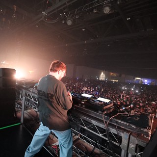 DJ Commanding a Massive Indoor Festival Crowd
