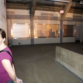 Woman Leaning Against Wall in Empty Warehouse Space