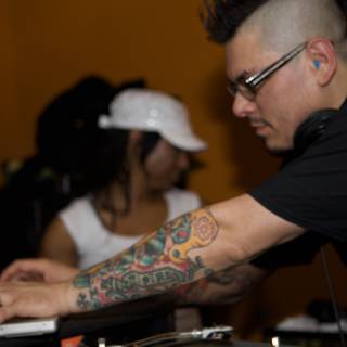 Black Shirted Deejay Flaunting Tattoos and Headphones