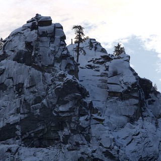 Snow-Covered Rocky Summit with Alpine Pines at Dusk